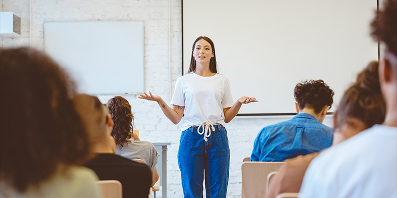 A teacher standing in front of a class to teach a class.