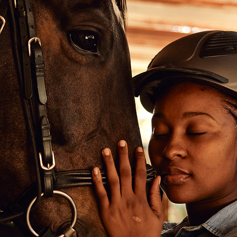 A woman gently strokes a horse's mane