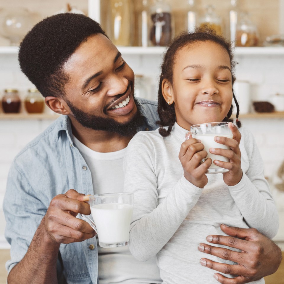 A father and daughter enjoying a glass of milk together.