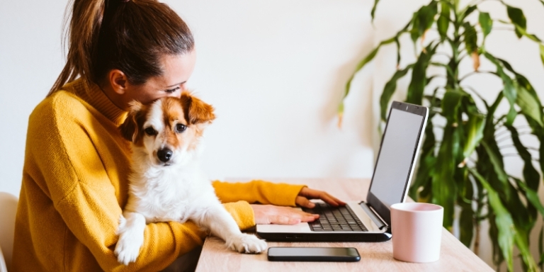 A woman and her dog sitting behind a computer
