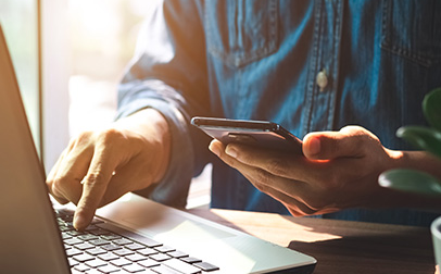 A man multitasking on a laptop and smartphone.